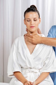 Relaxed young woman in bathrobe receiving neck massage by male masseuse at health spa