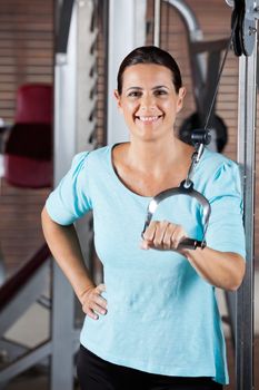 Portrait of happy woman training on machine in gym