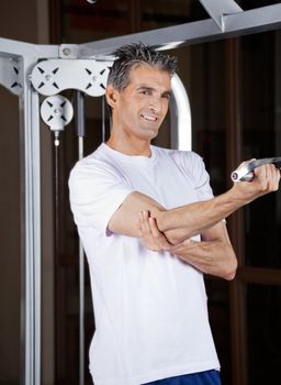 Happy mature man working out in fitness center