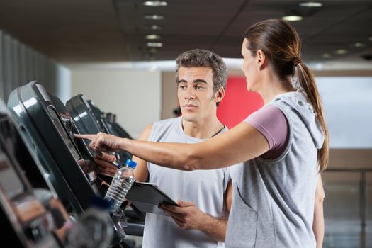 Woman asking instructor about machines at health club