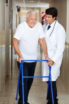Happy senior man being helped by a male doctor to walk the Zimmer frame