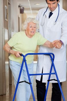 Young male doctor showing way to the patient using walker