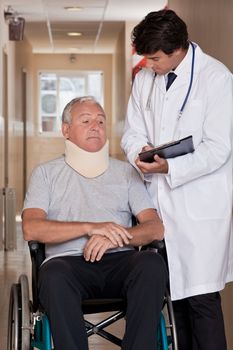 Doctor with patient wearing neck brace in wheelchair.