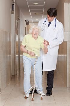 A doctor assisting a senior citizen onto her walking stick.