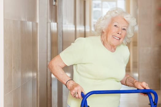 Portrait of a happy senior woman in hospital using Zimmer frame