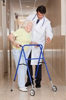 A doctor assisting a senior woman onto her walker.