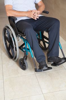 Low section of a senior man sitting in a wheelchair at hospital corridor