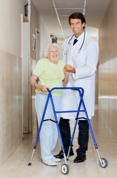 Full length portrait of a young male doctor assisting senior woman with her walker