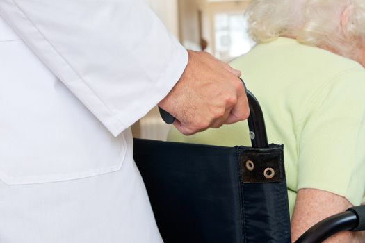 Midsection of a doctor assisting senior patient sitting in a wheel chair