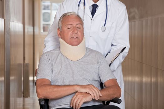 Doctor with patient wearing neck brace in wheelchair.