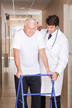 A doctor assisting a senior citizen onto his walker.