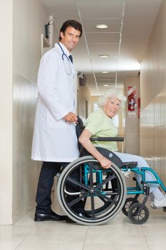 Side view of a happy young doctor assisting senior woman sitting in a wheel chair