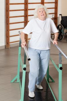 Full length portrait of a tired senior woman on walking track at hospital gym