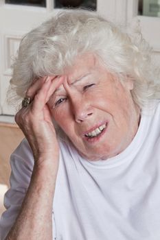 Portrait of a senior woman holding her head in pain .