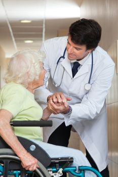 Happy young male doctor comforting senior patient at hospital