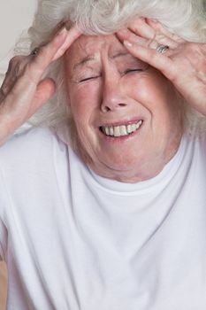 Portrait of a senior woman holding her head in pain .