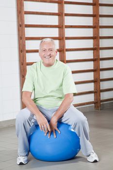 Happy Senior man sits on a fitball.