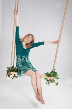 beautiful woman in a green dress on a swing