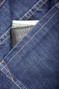 Wallet with dollars in the jeans pocket. Close-up photo