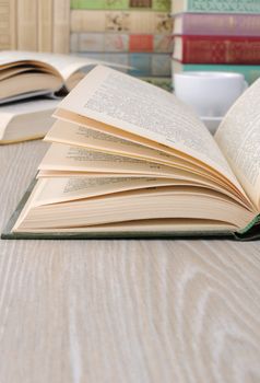 A fragment of an open book on the table among other books