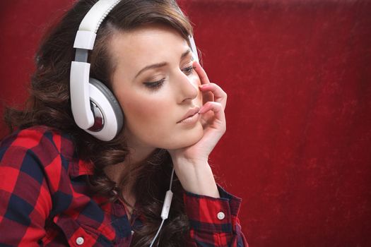 Young girl with laptop listen to music with headphones, near the sofa.