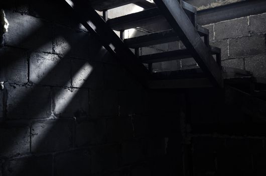 Old staircase in the dark basement. Natural light and shadows