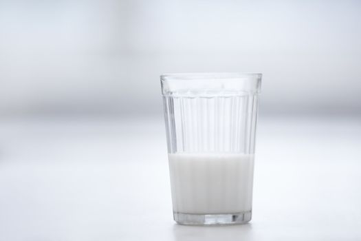 Glassful of milk on the table in white room