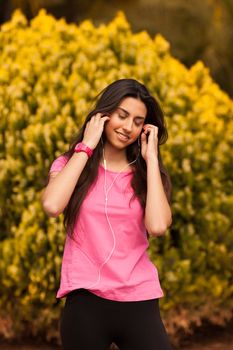 Young beautiful woman with sporty look enjoying with headphones outdoors