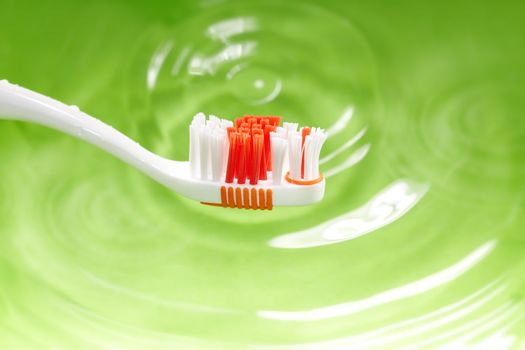 Close-up photo of the toothbrush on a green water background. Natural colors