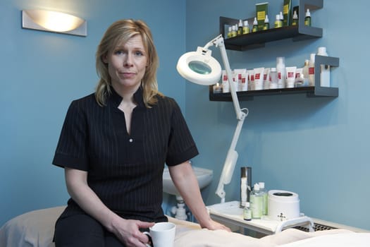 beautician sitting on massage table looking at camera