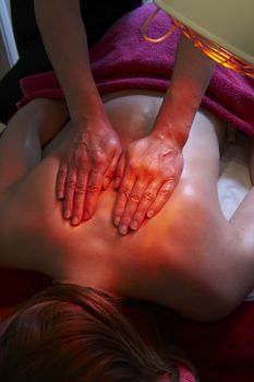 woman having back massage treatment under a heat lamp