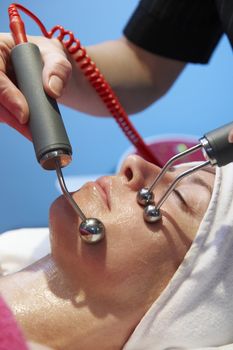 woman having a stimulating facial treatment from a therapist