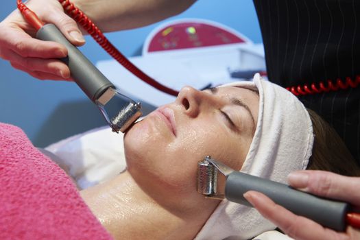 woman having a stimulating facial treatment from a therapist