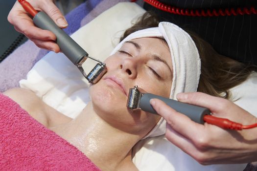 woman having a stimulating facial treatment from a therapist