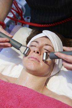 woman having a stimulating facial treatment from a therapist