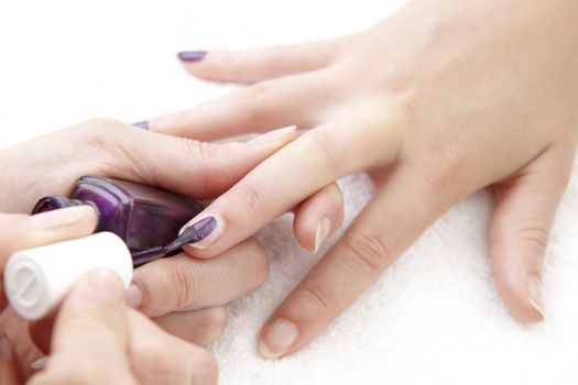 womans finger nails having purple varnish applied on white towel