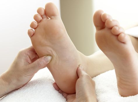 pair of feet being massaged by hands on white towel