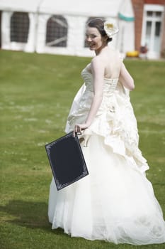 Pretty bride in wedding dress holding a blank board with space for copy