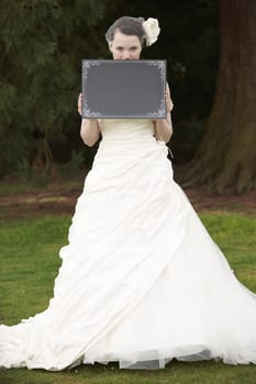 Pretty bride in wedding dress holding a blank board with space for copy