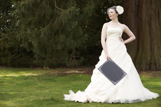 Pretty bride in wedding dress holding a blank board with space for copy