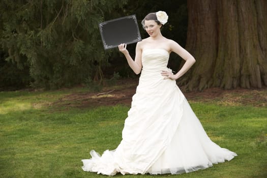 Pretty bride in wedding dress holding a blank board with space for copy