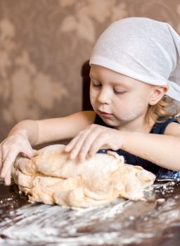 pretty little girl having fun kneads dough