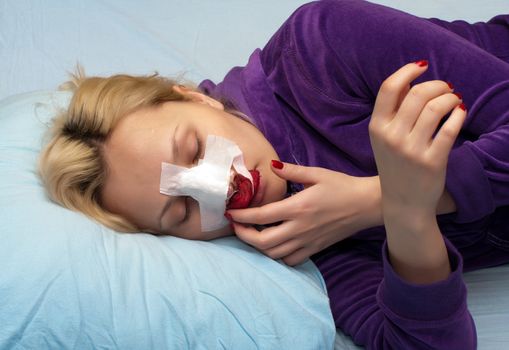 Girl in a blood-stained bandage after operation on a nose.