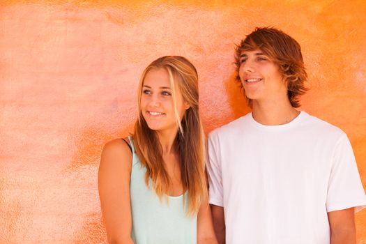 Young beautiful couple having great time over orange background