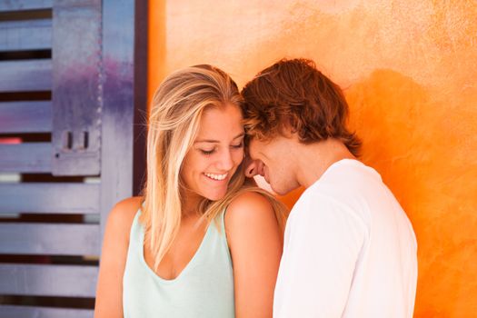 Young beautiful couple having great time over orange background
