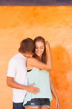 Young beautiful couple having great time over orange background