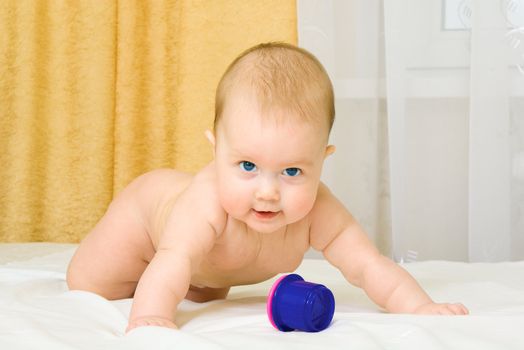 Small baby with toy on bed