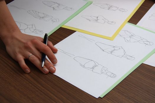 designer assessing fashion drawings on the collection of clothes