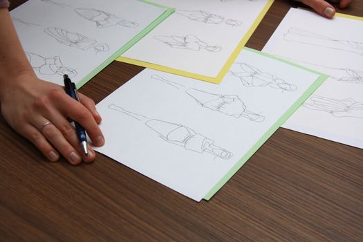 designer assessing fashion drawings on the collection of clothes