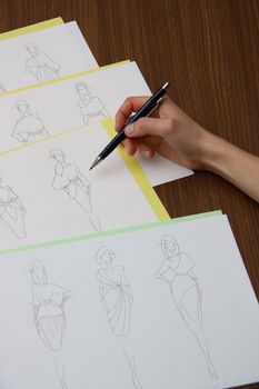 designer assessing fashion drawings on the collection of clothes